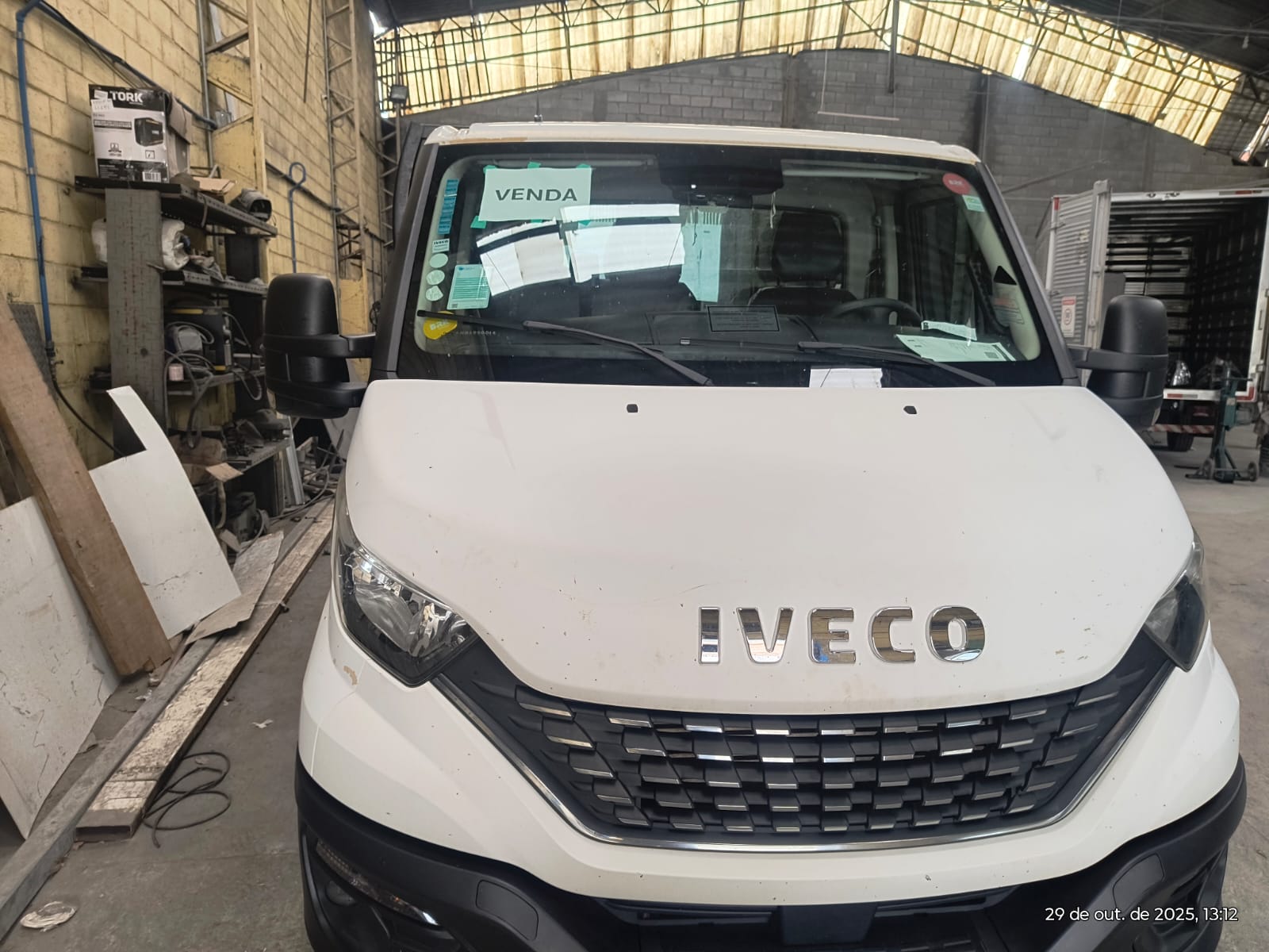 caminhão Iveco branco novo em galpão com placa VENDA no parabrisa